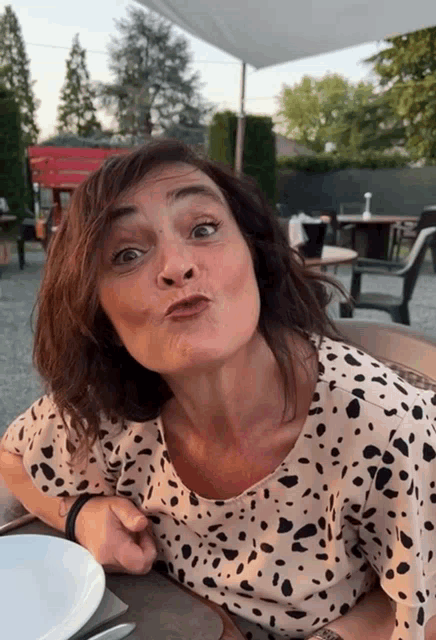a woman in a dalmatian print shirt is making a face