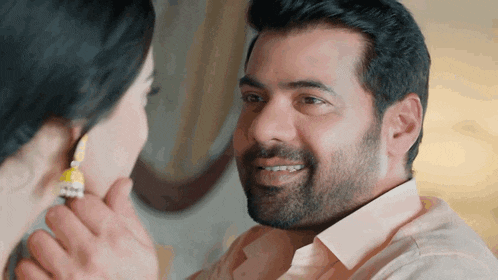 a man with a beard looks at a woman with earrings