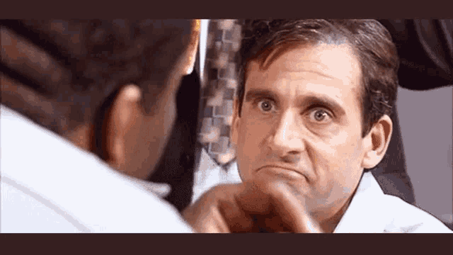 a man is looking at his face in a mirror and making a funny face .