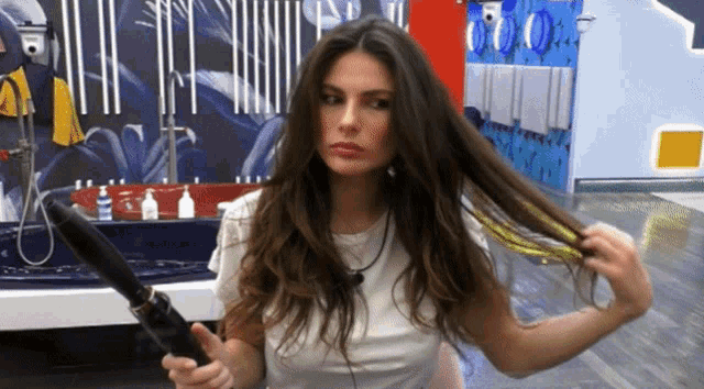 a woman in a white shirt is holding a hair dryer in her hand