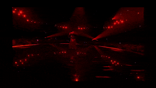 a woman is dancing on a stage in a dark room with red lights .