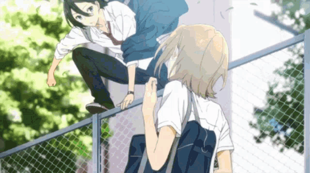 a boy and a girl are climbing a fence together
