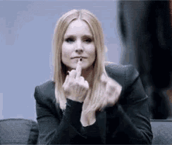 a woman in a black jacket holds her finger to her lips