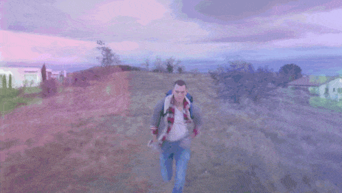 a man walking down a dirt road with a backpack