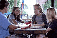 a group of people are sitting at a table with plates of food .