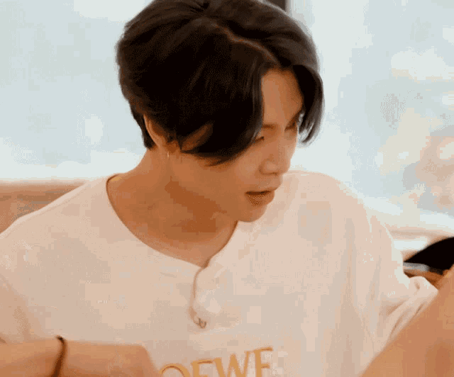 a man wearing a white t-shirt that says loewe on it
