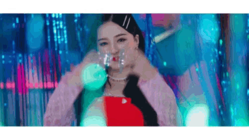 a woman is standing in front of a colorful background and holding a glass of water in her hand .