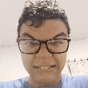a man wearing glasses and a blue shirt is smiling for the camera .