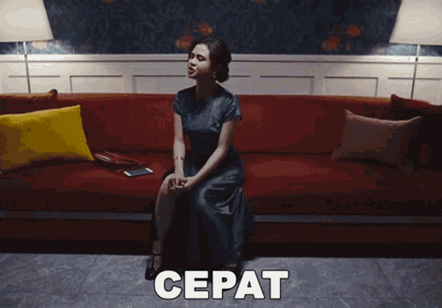 a woman in a green dress sits on a red couch with the word cepat written above her