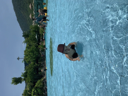 a child in a hat is swimming in a large pool