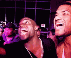 two men are laughing together in a crowded room
