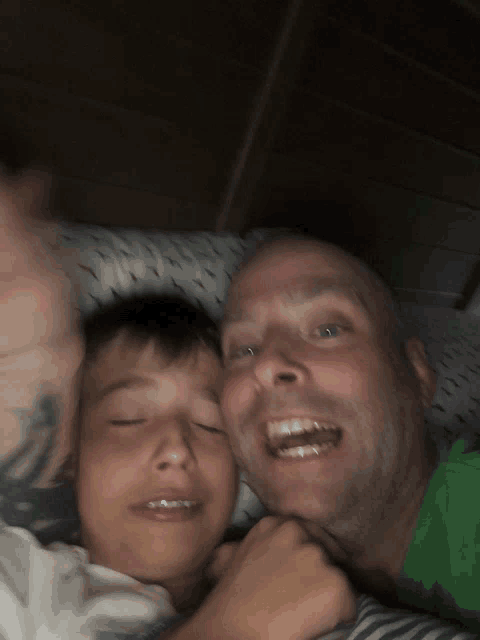 a man with a tattoo on his arm is smiling next to a boy