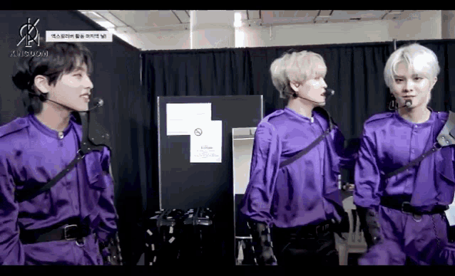 a group of young men in purple jumpsuits are standing next to each other .