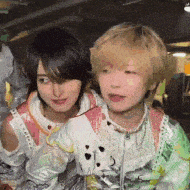 a man and a woman are standing next to each other in a room and looking at the camera .