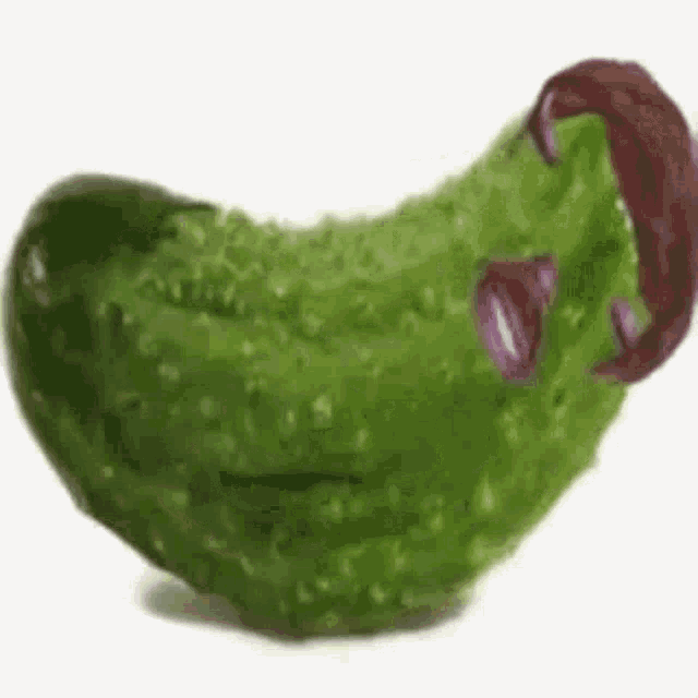 a green pickle with purple worms coming out of it 's mouth .