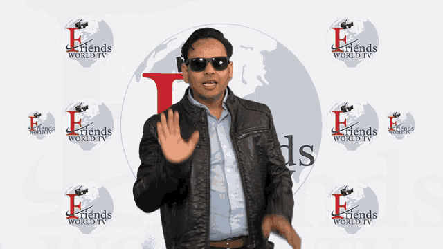 a man wearing sunglasses and a leather jacket stands in front of a wall that says friends world tv