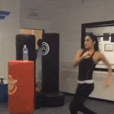 a woman is standing in front of a punching bag that says ' fighter ' on it