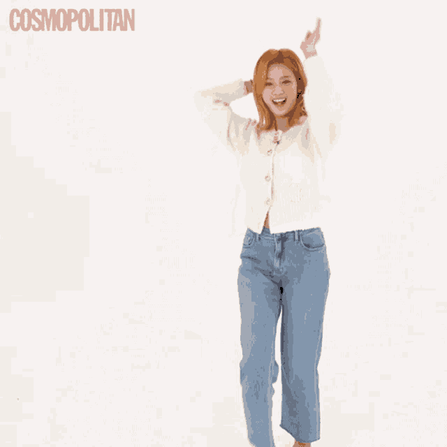 a woman in a white sweater and blue jeans is dancing in front of a white background .