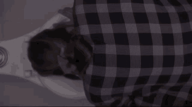 a person in a plaid shirt laying on a toilet