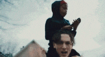 a man is carrying a child on his shoulders while the child looks at a cell phone .