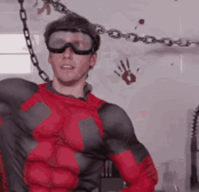 a man in a superhero costume is wearing goggles and chains around his neck