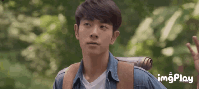 a young man with a backpack is looking at the camera with imgplay written on the bottom