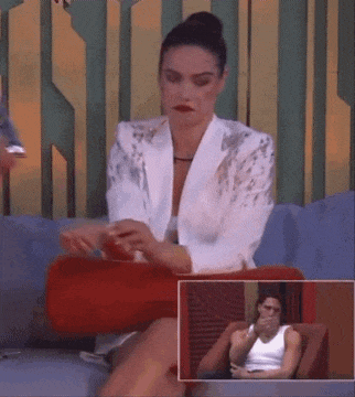 a woman in a white jacket is sitting on a couch with a red pillow .