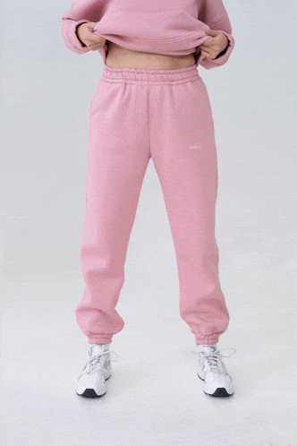a woman is wearing pink sweatpants and a pink sweatshirt