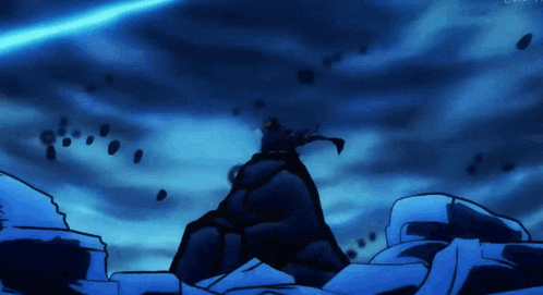 a person is standing on top of a mountain in the dark with a blue light coming from the sky .