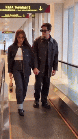 a man and woman are walking down an escalator in front of a naia terminal 3 sign