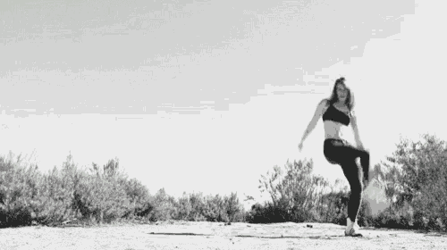 a woman is dancing on a dirt road in front of a green arrow .