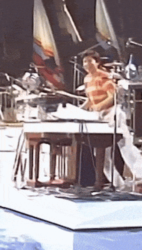 a man is playing a piano on a stage in front of a microphone