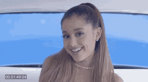 ariana grande is smiling and wearing a choker and pearls .