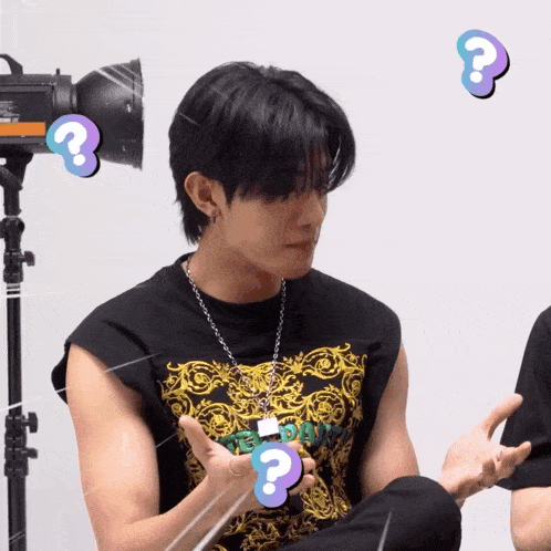 a man wearing a black sleeveless t-shirt with a question mark around his neck
