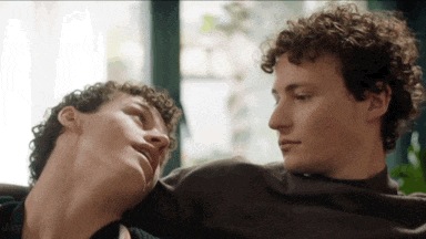 two men with curly hair are looking at each other while sitting next to each other .
