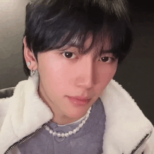 a close up of a person wearing a pearl necklace and earrings