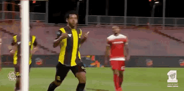 a soccer player in a black and yellow uniform is running on the field