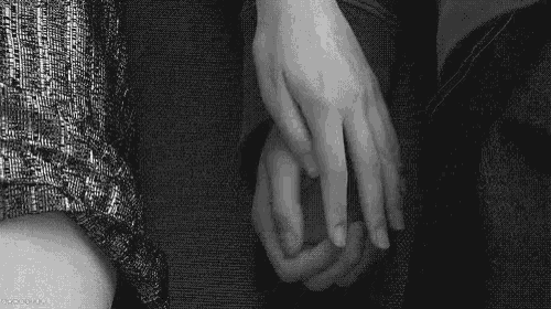 a black and white photo of two people holding hands .