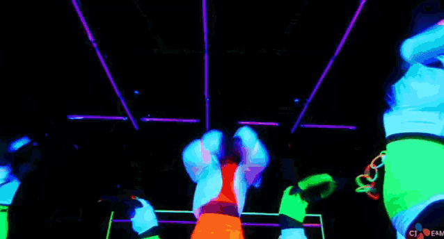 a group of women are dancing in a dark room with glow in the dark clothes