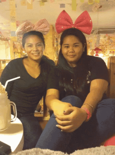 two women wearing pink bows on their heads are posing for a picture