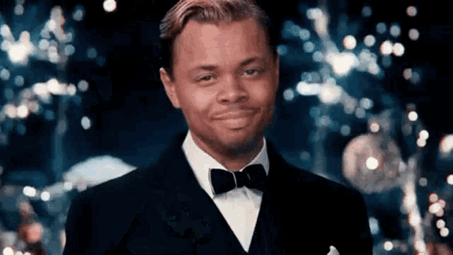 a man in a tuxedo and bow tie is smiling and looking at the camera .