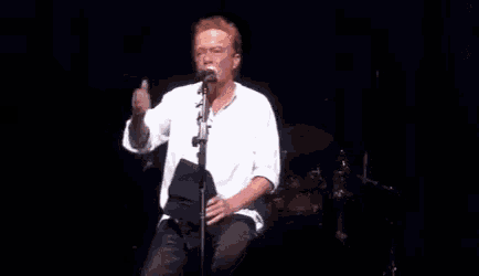 a man is sitting in front of a microphone on a stage .