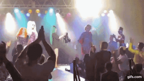 a group of people are dancing on a stage in front of a crowd of people .