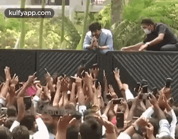 a man is standing in front of a crowd of people holding their cell phones .