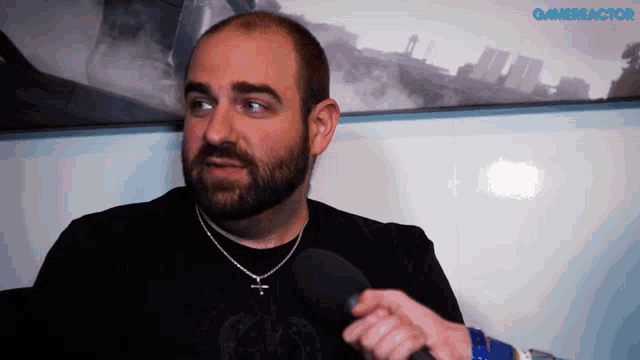 a man with a beard is holding a microphone in front of a wall that says gameractor on it