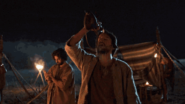 a man drinking from a bottle with his arms up in the air
