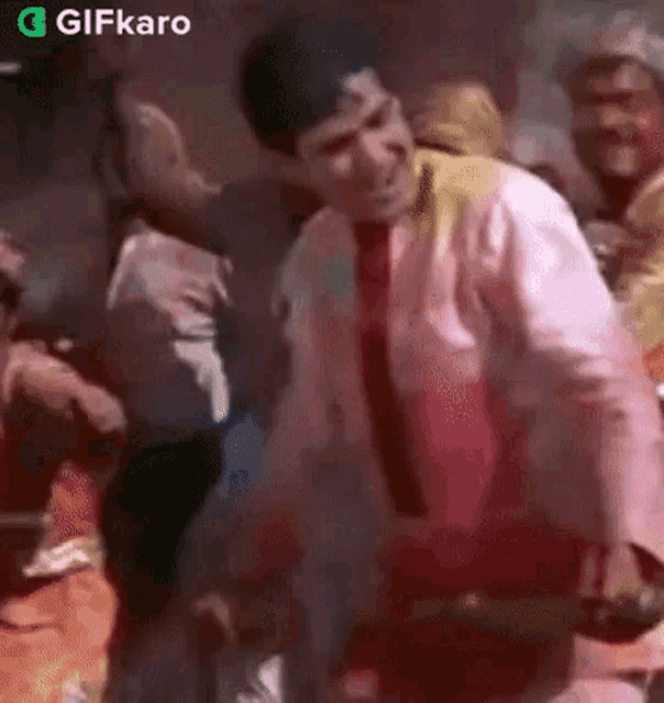 a man in a tie is dancing in a crowd of people at a party .