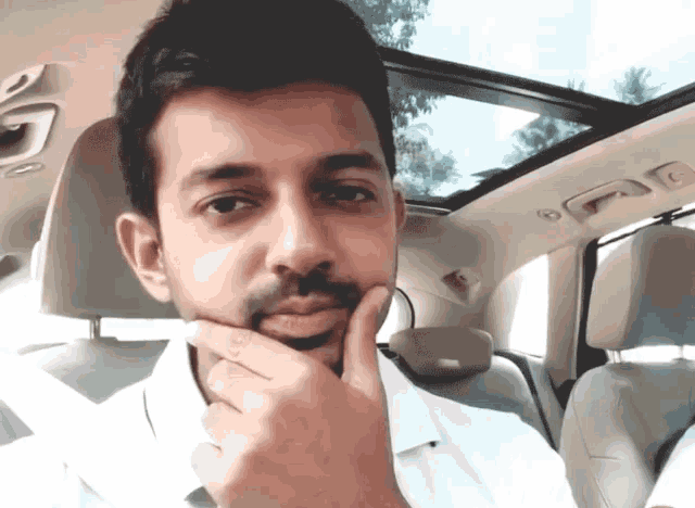 a man in a white shirt is sitting in the back seat of a car
