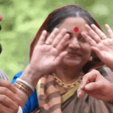 a woman with a red dot on her forehead covering her face
