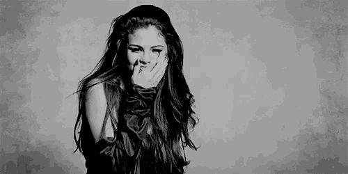 it is a black and white photo of a woman covering her mouth with her hand .